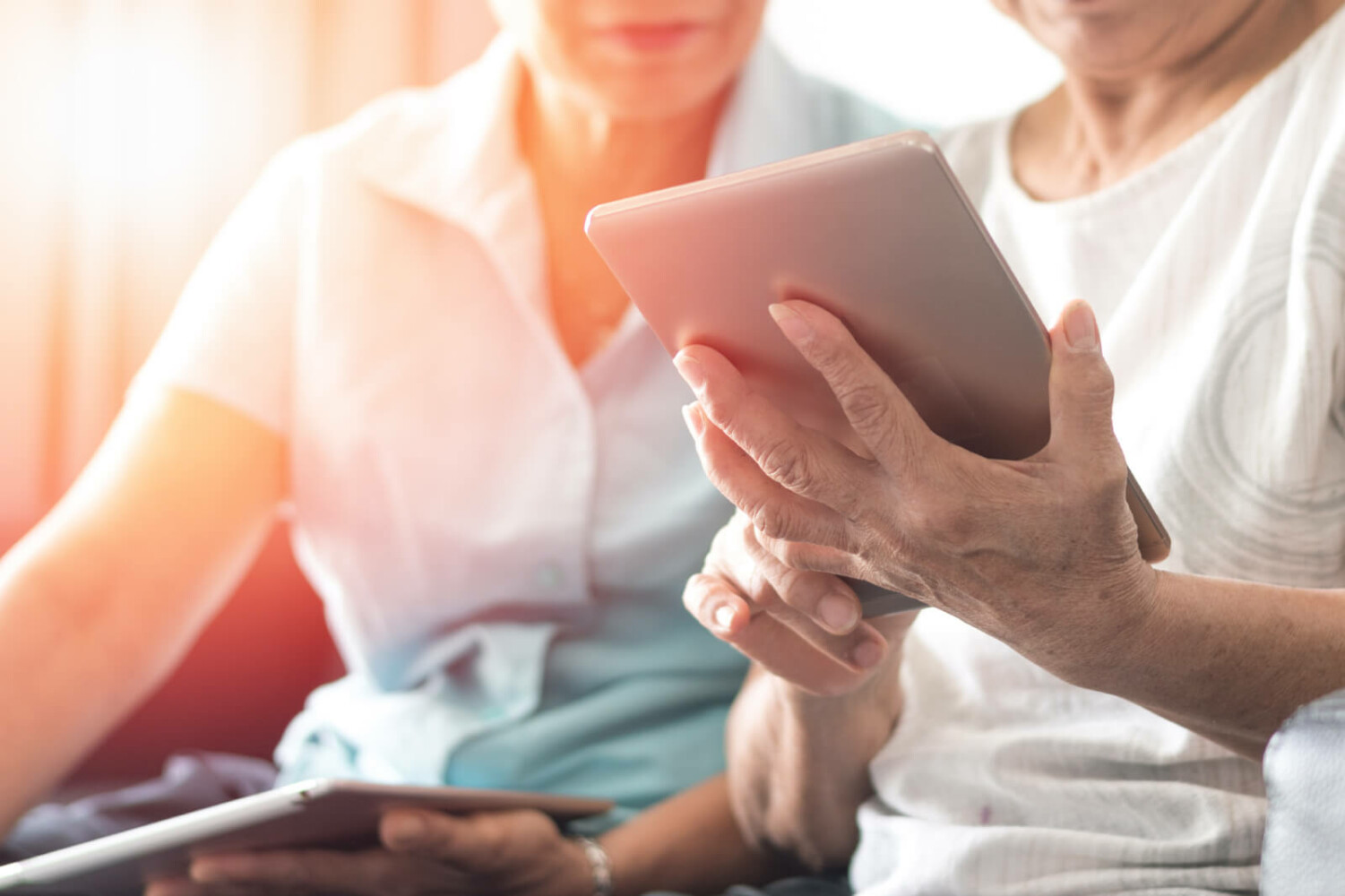 Ausschnitt von zwei Frauen. Sicht auf die Hände mit Tablet in der Hand