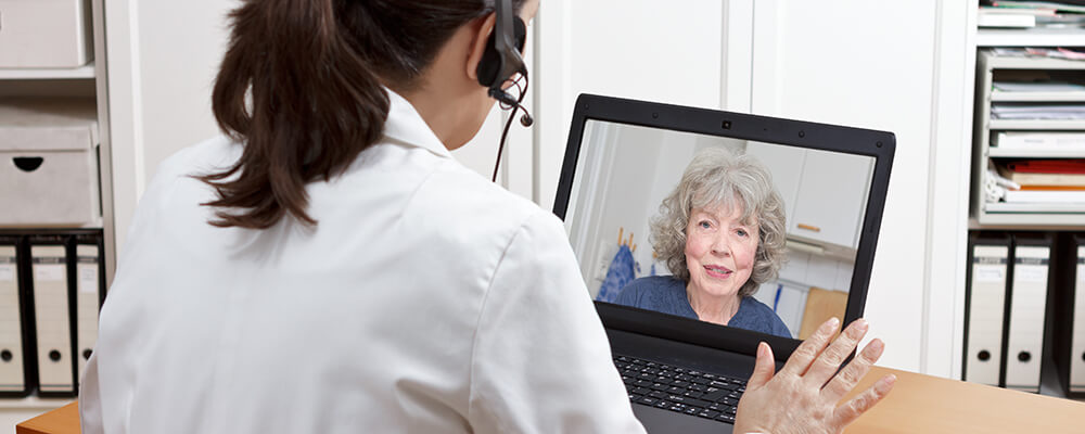 Ärztin unterhält sich mit einer Patientin per Video Call am Laptop.